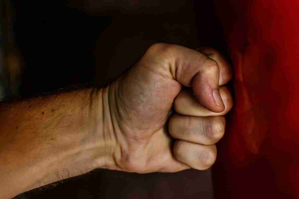 Close-up of a clenched fist against a dark red background, symbolizing anger