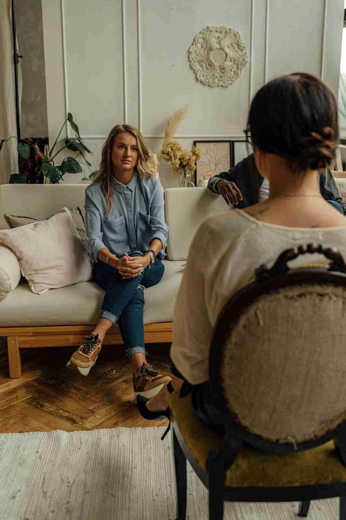Woman talking with a therapist while seated on a couch in a cozy therapy office